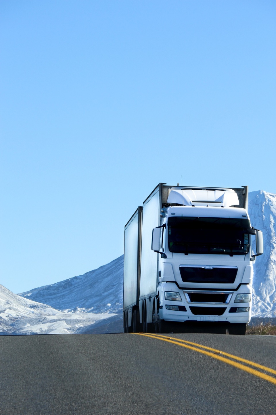 Large truck driving uphill with snowy mountains